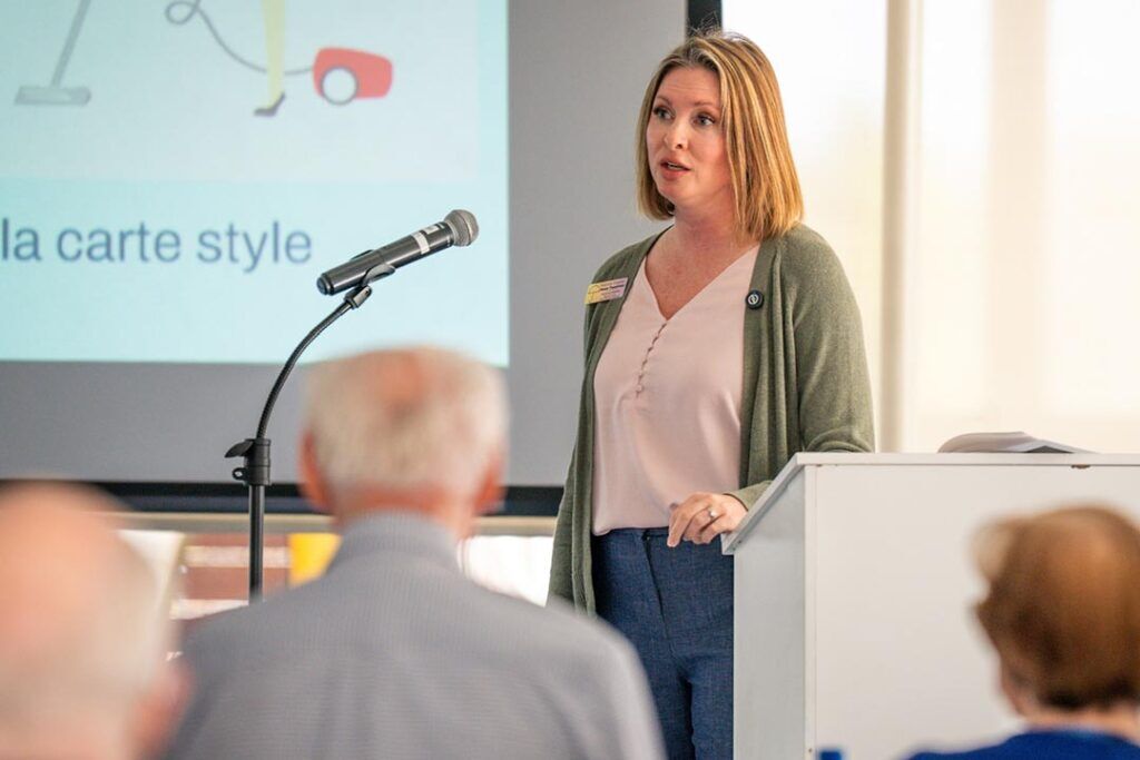 Amanda Ralstin speaks from a lecturn in front of a project screen at our Empowered Living Senior Seminar